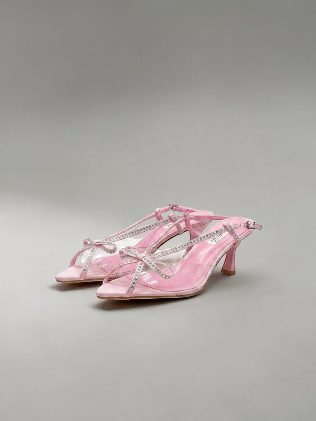 Day One Concept Store pink slingback sandals with clear straps, bow details, and rhinestone embellishments. Pointed toe with a stiletto heel.