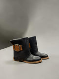 Day One Concept Store black faux leather boots with tan buckle detail and robust sole. Fold-over cuff design.