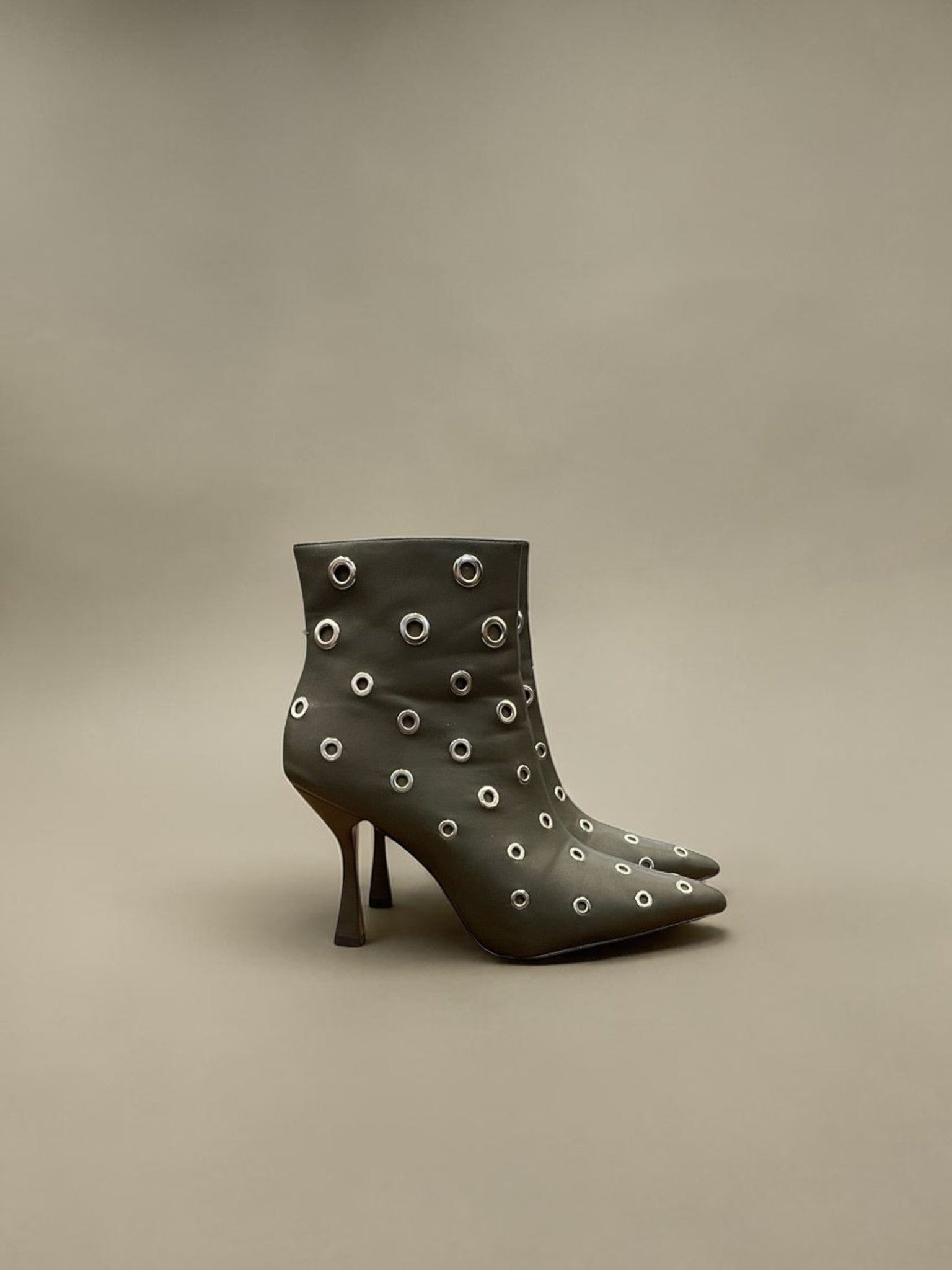 Day One Concept Store black ankle boots with pointed toe, stiletto heel, and all-over silver eyelet details.