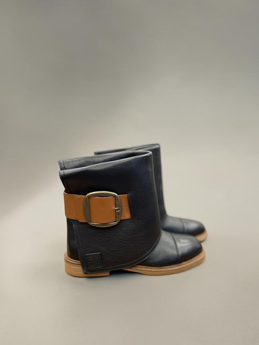 Day One Concept Store black faux leather boots with tan buckle and robust sole. Rock-inspired ankle boots.