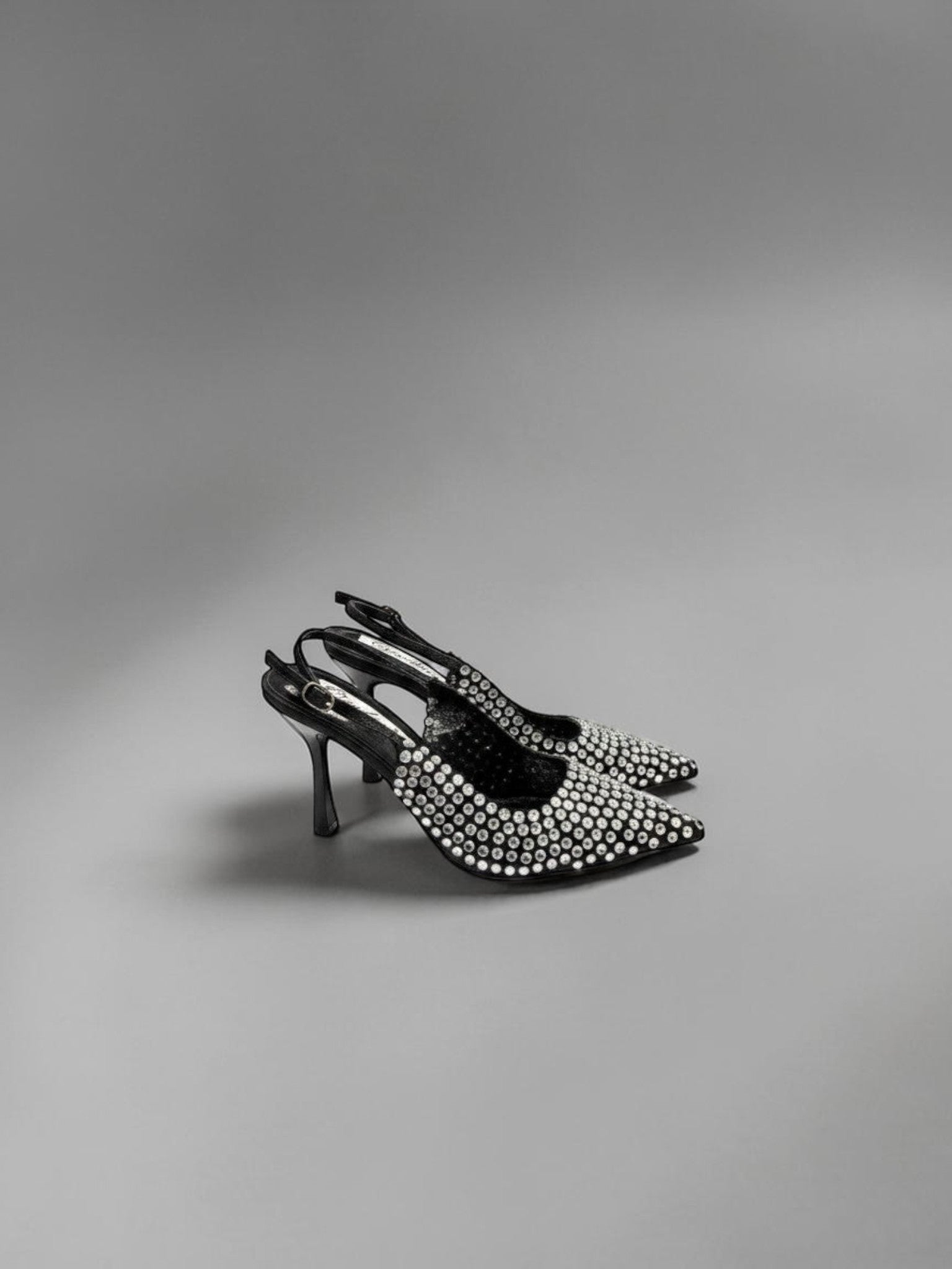Day One Concept Store black slingback heels with pointed toe and all-over rhinestone embellishments. Adjustable ankle strap.