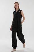 Day One Concept Store black sleeveless wide-leg jumpsuit with hood and star detail. Model wears beige flats.