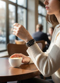 Day One Concept Store black studded rigid bracelet on a woman's wrist, paired with a cream sweater.