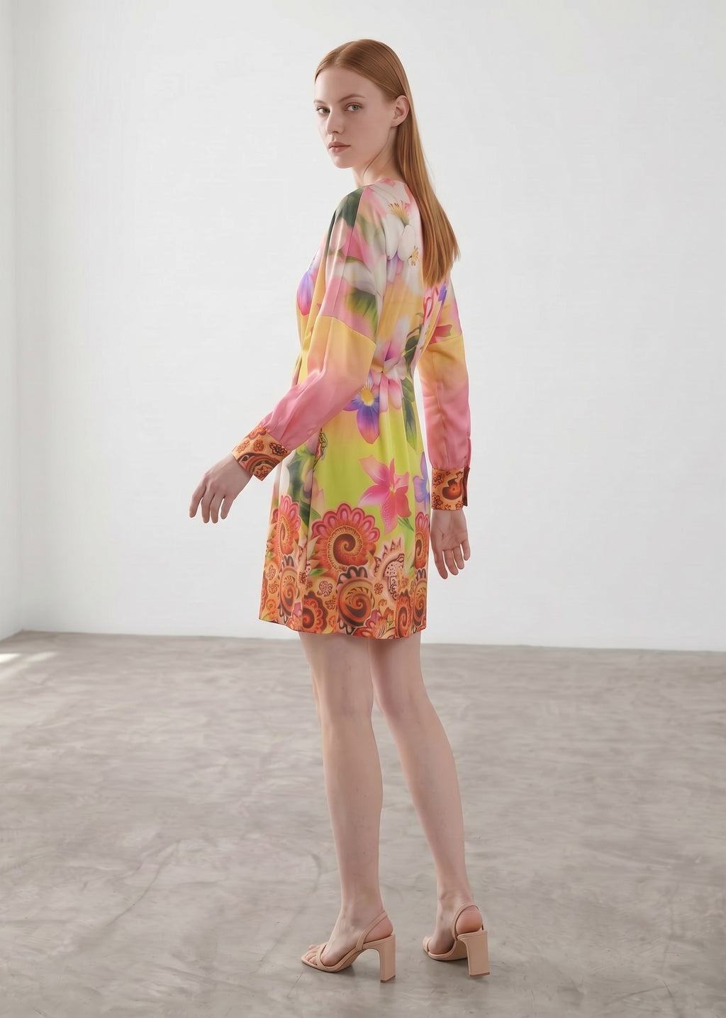 Day One Concept Store short floral print V-neck dress with a cinched waist and paisley border. Vibrant pink, yellow, and orange.