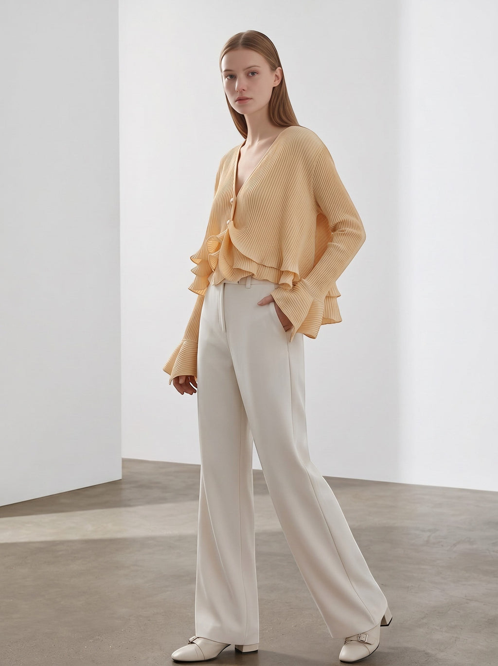 Day One Concept Store peach pleated V-neck blouse with pearl buttons and ruffled flared sleeves, paired with cream trousers.
