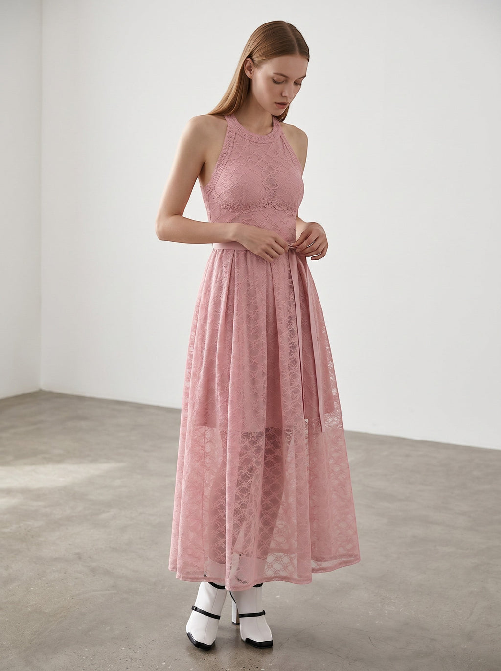 Day One Concept Store pink lace halter neck maxi dress with sheer overlay and fluid skirt. Model wears white heels and blue socks.
