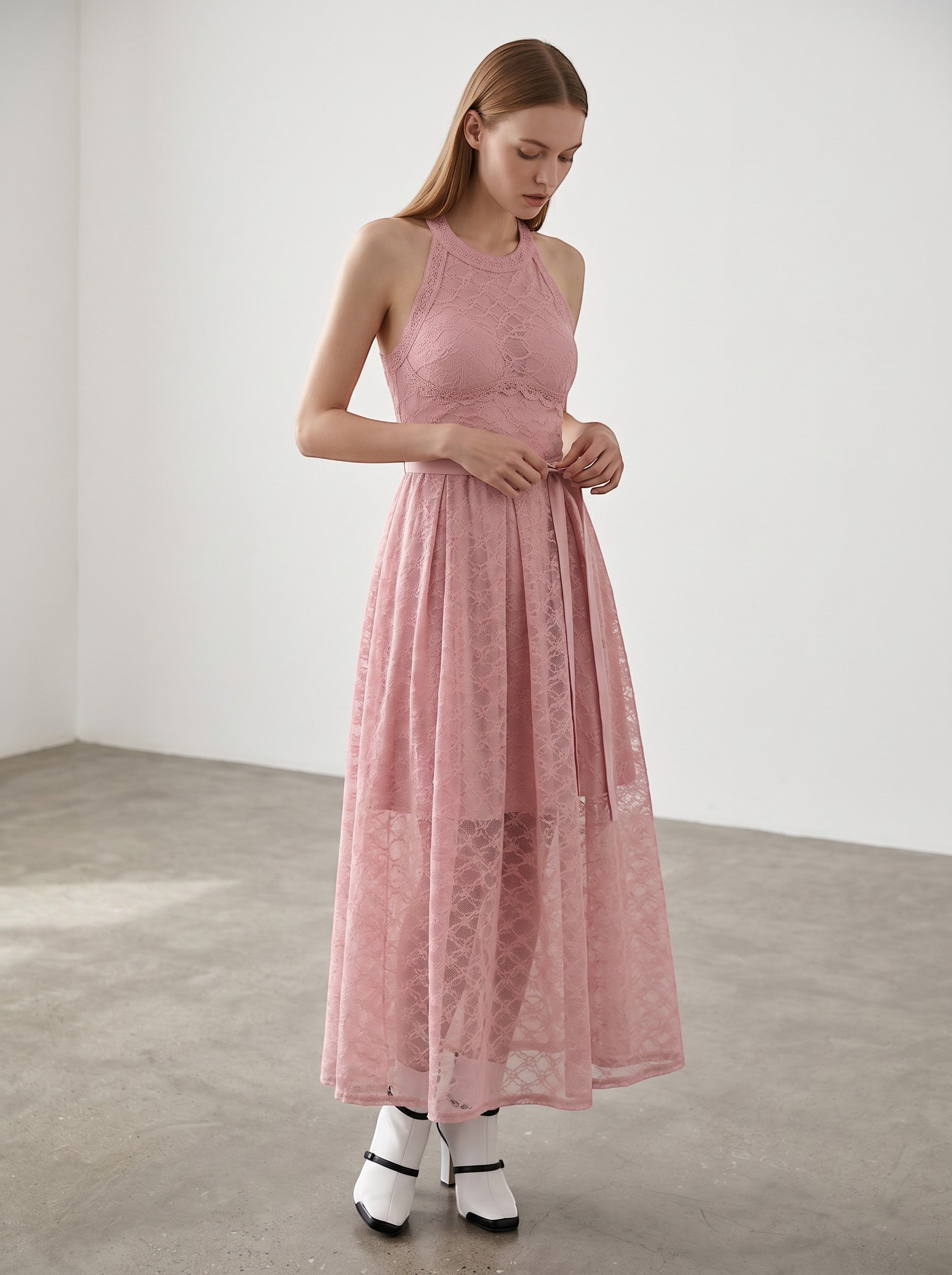Day One Concept Store pink lace halter neck maxi dress with sheer overlay and fluid skirt. Model wears white heels and blue socks.