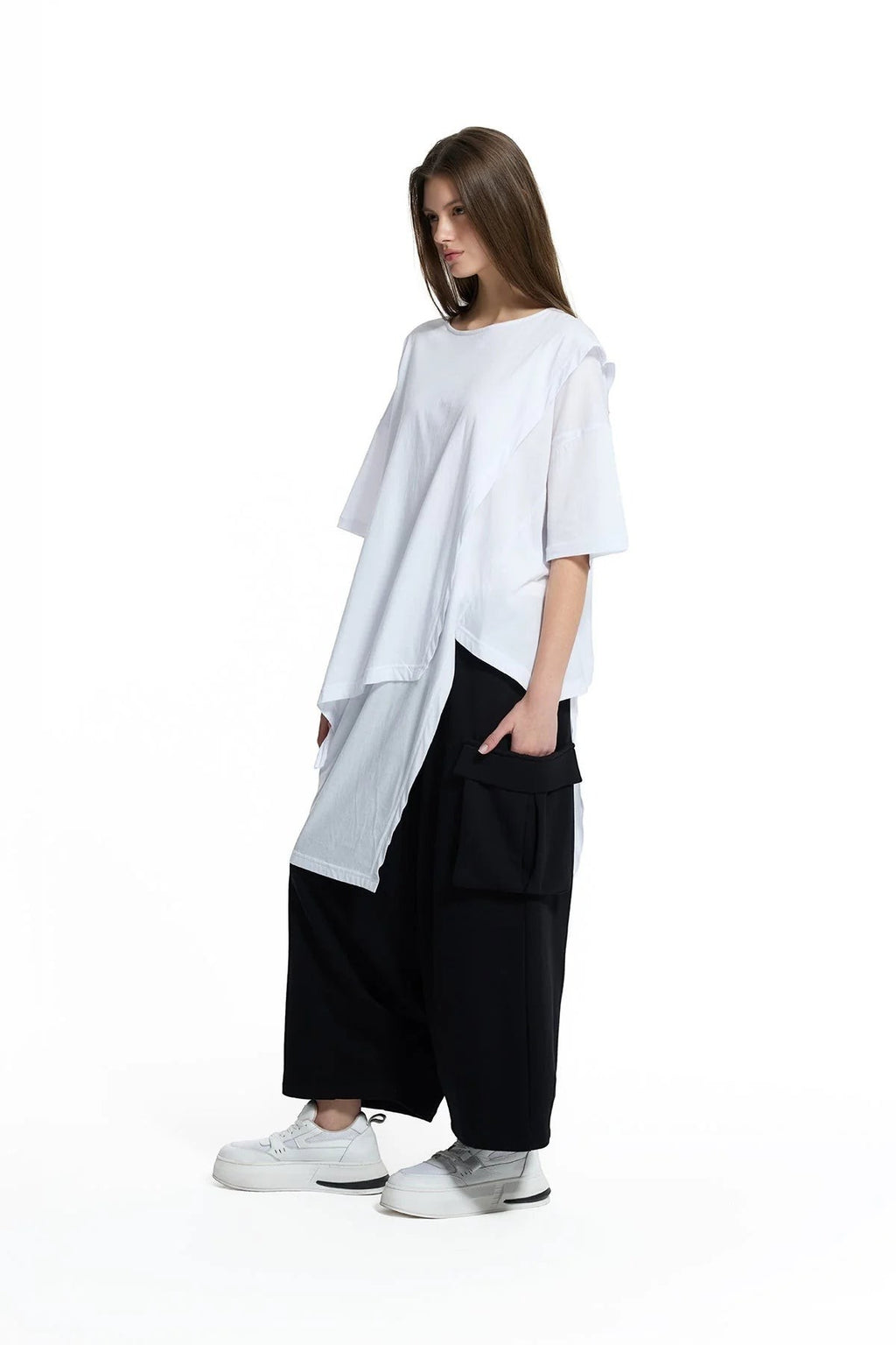 Day One Concept Store white oversized cotton t-shirt with asymmetric hem and layered detail, worn by a model with black wide-leg pants.