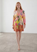 Day One Concept Store yellow floral print V-neck mini dress with paisley border. Model wears dress with long sleeves and cinched waist.