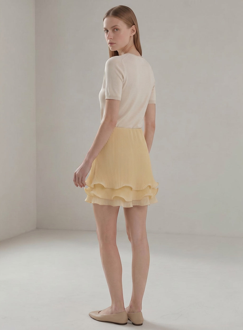 Day One Concept Store light yellow pleated midi skirt with tiered ruffle hem, worn by a model in a studio.
