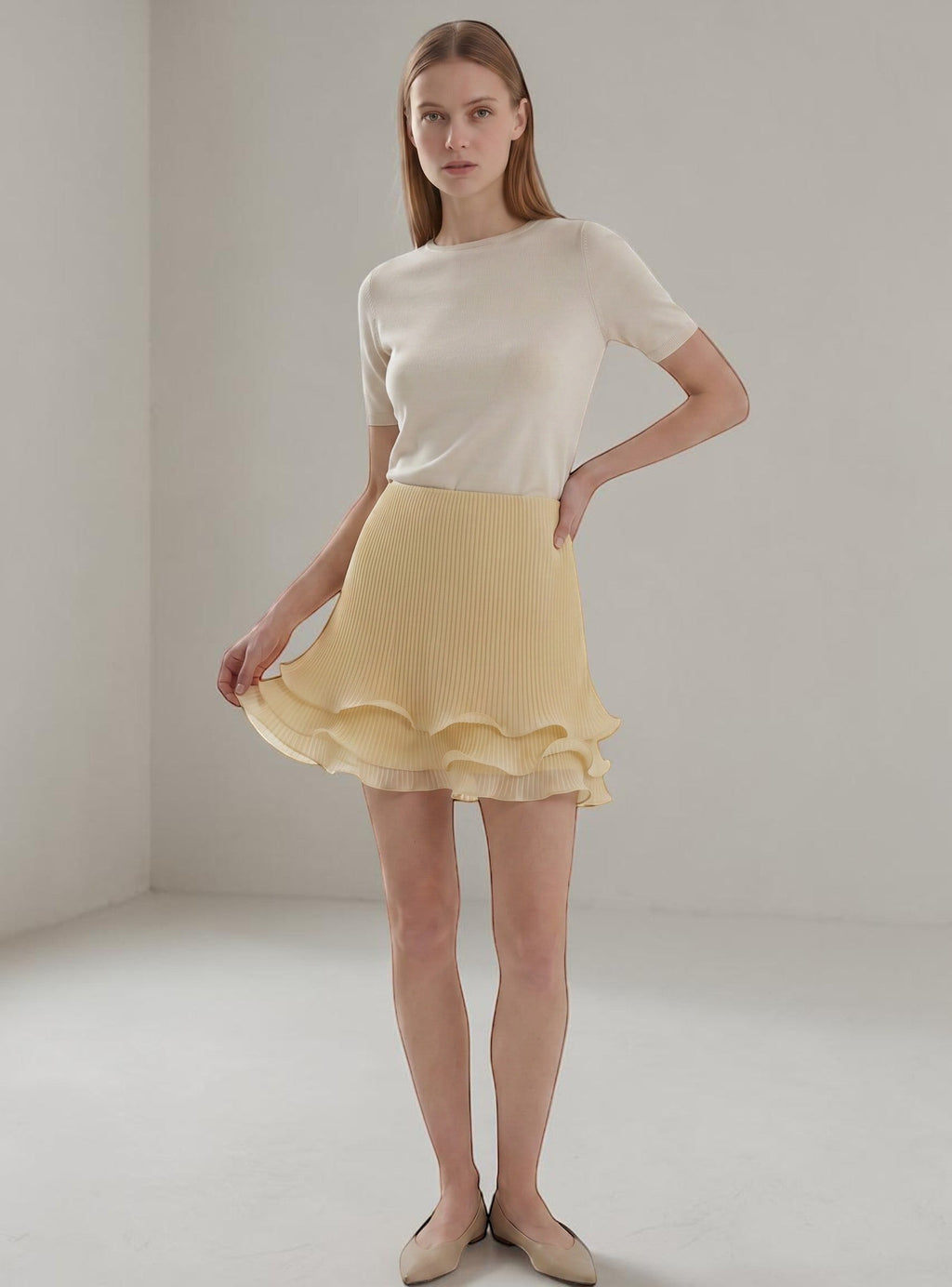 Day One Concept Store light yellow pleated midi skirt with tiered ruffle hem. Model wears a cream top.
